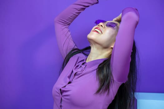 Cheerful asian lady raise hands arms smiling happy isolated over purple violet background. High quality photo