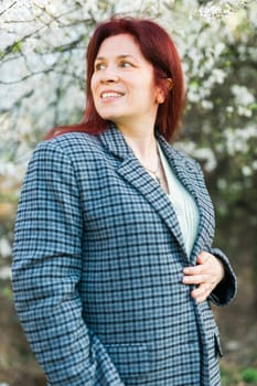 Beautiful happy millennial woman enjoying smell in a flowering spring garden. Blooming tree time.