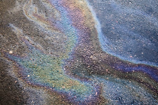 Oil rainbow gasoline spill on asphalt. Rainbow stains of oil and gasoline