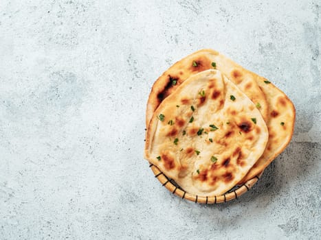 Fresh naan bread on gray cement background with copy space. Top view of several perfect naan flatbreads
