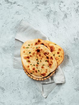 Fresh naan bread on gray cement background with copy space. Top view of several perfect naan flatbreads. Vertical