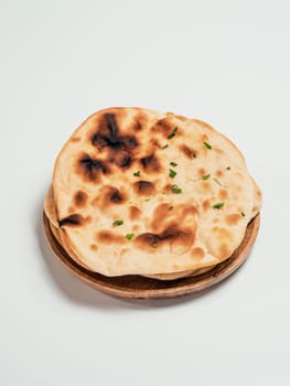 Fresh naan bread on plate isolated on white background. Stack of several perfect naan flatbreads on white.