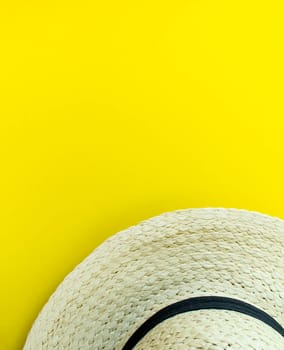 Flatlay, summer vacation. Straw hat on a yellow background. Vertical background. Background for advertising.