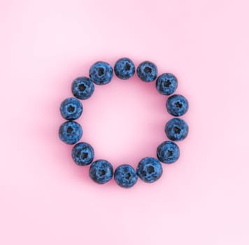 Creative layout with fresh ripe berries. Blueberry on pink background with round empty circle in center for copy space. Can use for your design, promo, social media, Top view. Square format for SMM.