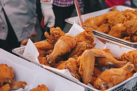 Image captures golden crispy fried chicken served at outdoor market. Street food delight with succulent pieces inviting passersby to indulge.