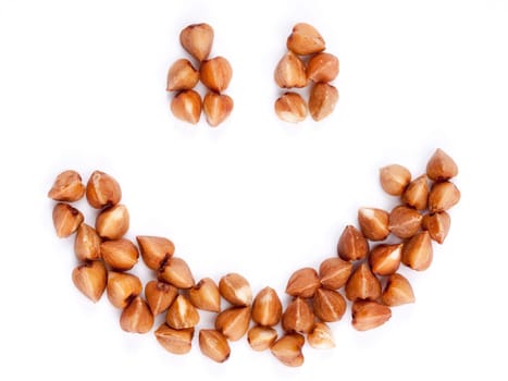 Smile of raw buckwheat as background. Isolated on white. Top view or flat lay. Healthy food and diet concept