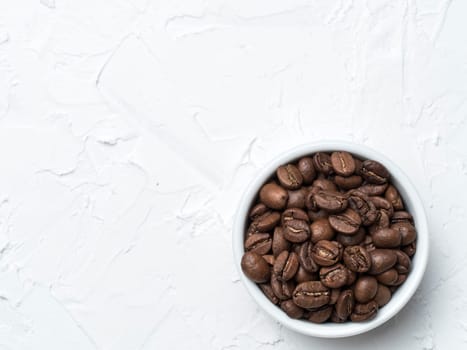 Coffee beans with copy space. Brown coffee beans on white concrete textured background. Top view or flat lay. Copy space.