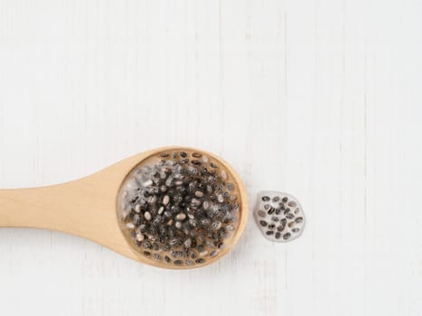 Wet chia seeds or chia-egg in wooden spoon on white wooden background. Egg replacers, plant based eggs, vegans replace eggs concept Copy space for text.