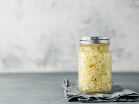 Sauerkraut in glass mason jar. Pickling cabbage at home on table. The best natural probiotic. Homemade kraut., copy space for text