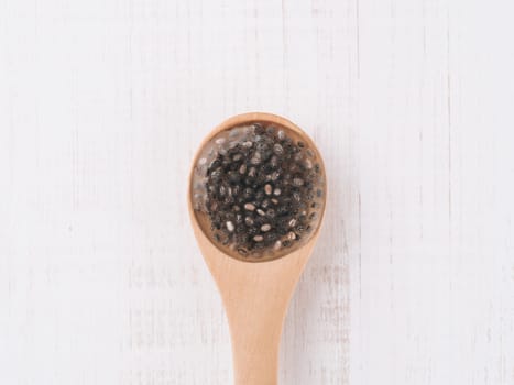 Wet chia seeds or chia-egg in wooden spoon on white wooden background. Egg replacers, plant based eggs, vegans replace eggs concept