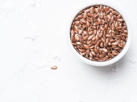 Flax seeds with copy space. Brown flax seed on white concrete textured background. Top view or flat lay. Copy space. Healthy food and diet concept