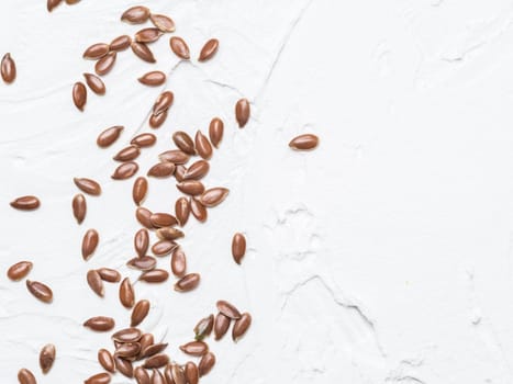 Flax seeds with copy space. Brown flax seed on white concrete textured background. Top view or flat lay. Copy space. Healthy food and diet concept