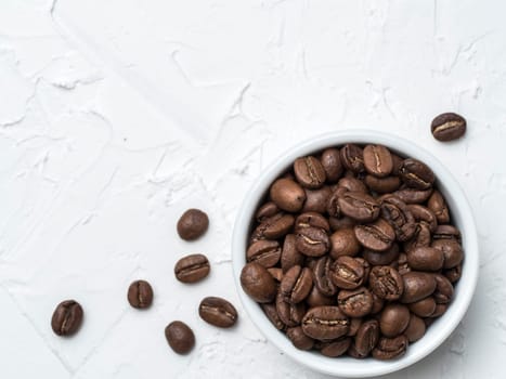 Coffee beans with copy space. Brown coffee beans on white concrete textured background. Top view or flat lay. Copy space.