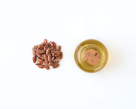 Linen seeds and linen raw oil isolated on white background. Heap of flax seeds and raw flax seed oil in small glass bottle isolated on white with clipping path, top view or flat lay. Macro