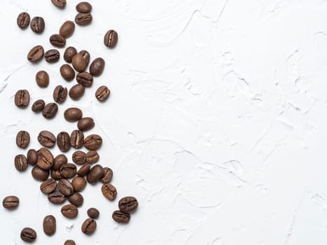 Coffee beans with copy space. Brown coffee beans on white concrete textured background. Top view or flat lay. Copy space.