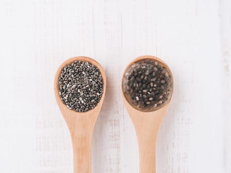 Dry chia seeds and wet chia seeds or chia-egg in wooden spoons on white wooden background. Egg replacers, plant based eggs, vegans replace eggs concept