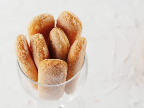 Top view of ladyfinger biscuit cookie in glass jar on white concrete background. Italian cookie savoiardi. Copy space.