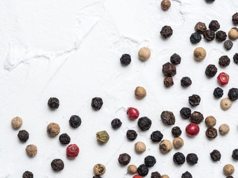 Assorted peppercorns. Medley trio colorful peppercorn on white textured concrete background with copy space. Top view or flat lay.