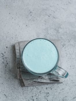 Trendy drink: Blue latte. Top view of hot butterfly pea latte or blue spirulina latte on gray cement textured background. Copy space for text. Top view or flat lay.