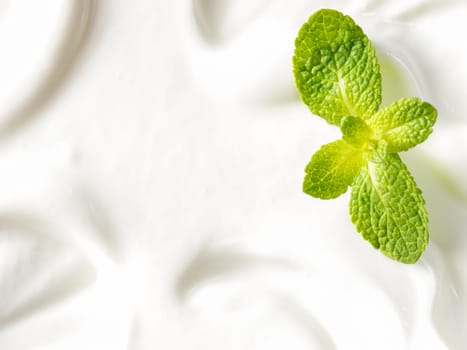 greek yogurt or sour cream texture and mint leaf close up with copy space. Top view or flat lay