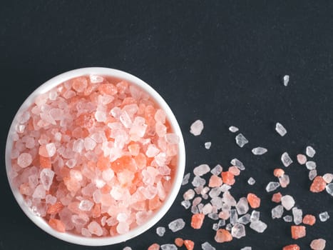 Himalayan pink salt in crystals on black stone background. Copy space