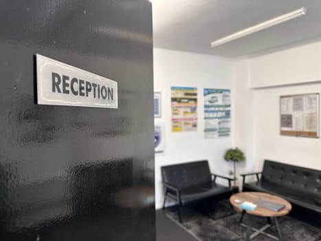 Selective focus on reception sign on the door, waiting area on the background