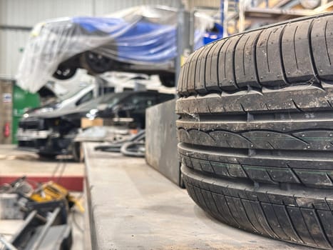 Close up of a car tyre, dismantles cars on the lift on background at car repair shop