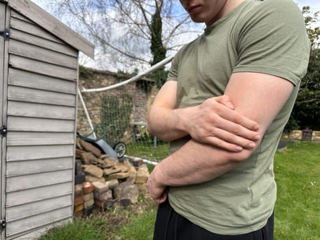Cropped shot of a man rubbing his injured elbow outdoors