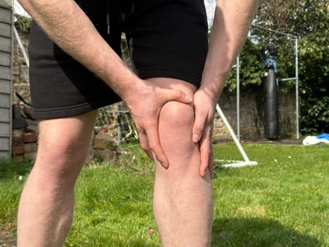 Unrecognizable man rubbing his injured aching knee