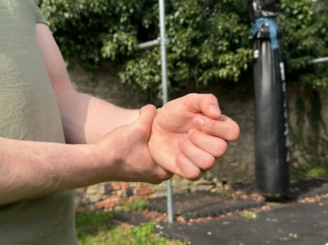 Unrecognizable man rubbing his aching wrist, injured after workout