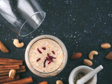 Thandai or Sardai cold drink made during Holi festival. Cold milk drink in glass, with ingredients - nuts and spices. Copy space