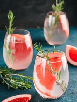 infused detox water or alcoholic or non-alcoholic cocktail with grapefruit and rosemary in glass on green and black cement background. healthy eating or holyday drink concept, copy space for text