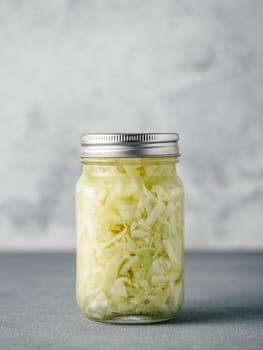 Sauerkraut in glass mason jar. Pickling cabbage at home on table. The best natural probiotic. Homemade kraut., copy space for text. Vertical.
