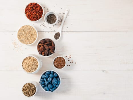 Various superfoods in small bowl on white wooden table.Selection super food.Superfood as blueberry, chia, raw cocoa bean, goji, hemp seeds, quinoa, brown rice. Copy space for text.Top view or flat lay