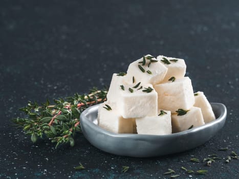 Greek cheese feta with thyme on dark blue table. Copy space