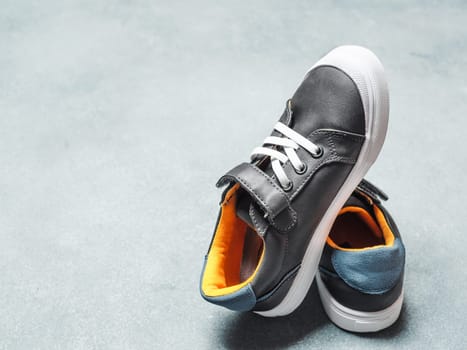 pair of new kids or adult sneakers on gray stone background, top view. Flat lay gray and yellow or mustard color sneakers shoes with copy space for text or design.