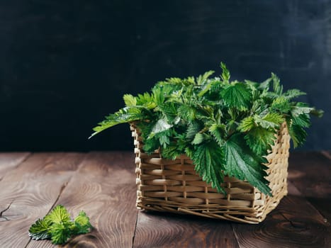Basket of fresh stinging nettle leaves on wooden table. Nettle leaf with copy space. Horizontal