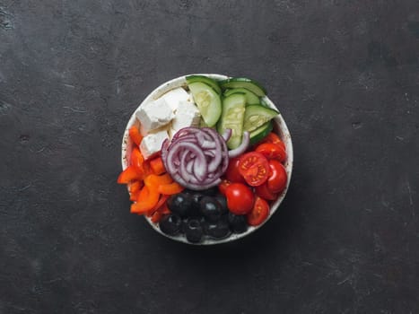 Greek Salad Bowl on dark black background, copy space. Above view of Bowl Greek Salad. Trendy food. Idea, recept and concept of modern healthy food.