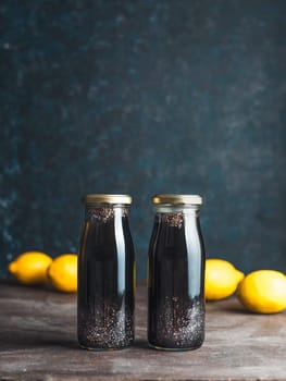 Detox activated charcoal black chia water or lemonade with lemon. Two bottle with black chia infused water. Detox drink idea and recipe. Vegan food and drink. Vertical.
