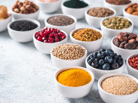 Various superfoods in smal bowl gray concrete background. Superfood as chia, spirulina, raw cocoa bean, goji, hemp, quinoa, bee pollen, black sesame, turmeric. Copy space for text.