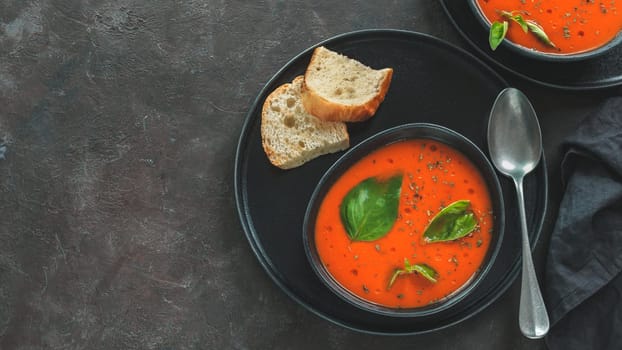 Gaspacho soup in black bowl. Traditional spanish cold soup puree gaspacho or gazpacho on dark background with copy space for text. Top view or flat lay. Banner