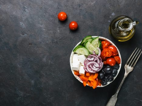 Greek Salad Bowl on dark black background, copy space. Above view of Bowl Greek Salad and ingredients. Trendy food. Idea, recept and concept of modern healthy food.