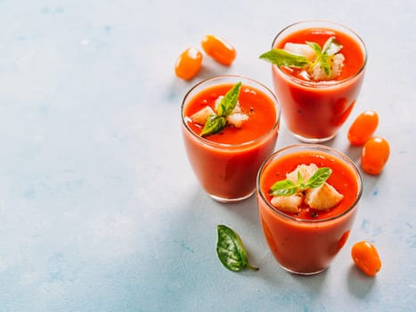 Delicious gaspacho soup in glass. Traditional spanish cold soup puree gaspacho or gazpacho on gray cement background with copy space for text. View from above or top view or flat lay