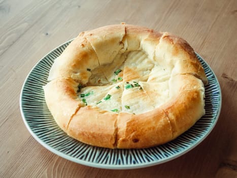 tasty tandoor baked bread on plate. National asian bread - tandoor bread with green onion on wooden table. Natural day light