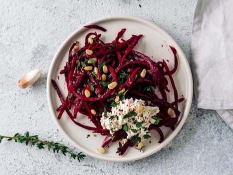 Raw beetroot spaghetti salad with soft cheese,nuts,thyme.Vegetable noodles - Fresh Beetroot Noodles with Ricotta and fresh thyme on plate. Copy space.Clean eating, raw vegetarian food concept.Top view