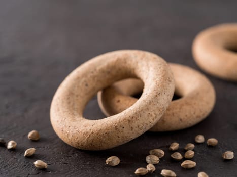 Ring-shaped cracknel with whole grain hemp seed flour and hemp seeds on black background. ring-shaped cracknel close up. Copy space