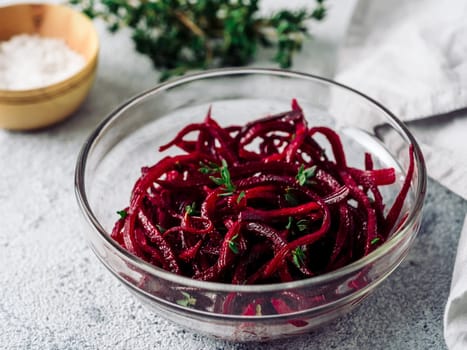 Raw beetroot noodles salad. Vegetable noodles - beet spaghetti in glass plate over gray cement background. Copy space for text. Ideas and recipe for Clean eating, raw vegetarian food concept.