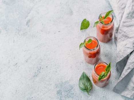 Delicious gaspacho soup in glass bottles. Traditional spanish cold soup puree gaspacho or gazpacho on gray cement background with copy space for text. View from above or top view or flat lay