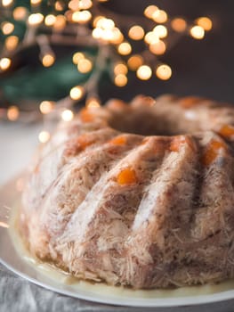 Homemade delicious jelly meat on festive Christmas table. Close up view of perfect jellied meat, aspic, galantine with carrot. Copy space for text. Vertical.