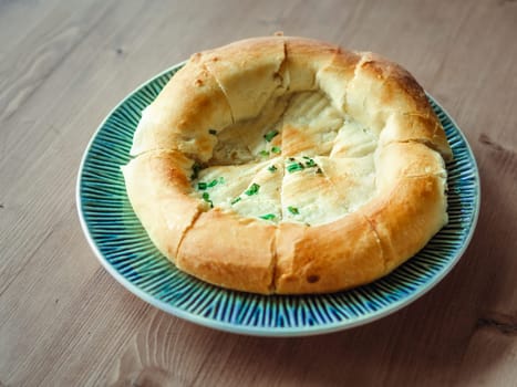 tasty tandoor baked bread on plate. National asian bread - tandoor bread with green onion on wooden table. Natural day light